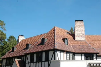 A house with a complex roof structure featuring red tiles, showcasing the craftsmanship of Mid-Peninsula Roofing Inc. in Burlingame.
